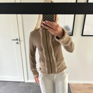 Beige cardigan jacka från Freeman T. Porter - Säljer en beige cardigan jacka från Freeman T. Porter med stickade partier, fuskpälsdetaljer och dragkedja framtill. Bra skick och i storlek M.