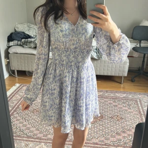Blommig klänning - Fin blå sommar klänning med blommor på🌸 Har använts men inget som syns alls bara att den är uppsydd vid v-ringningen🥰 