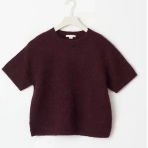 Vinröd stickad kortärmad tröja - Mysig vinröd stickad tröja med korta ärmar och rund hals. Den fluffiga känslan gör den både trendig och bekväm att bära till jeans, shorts eller kjol. Storlek 152 men sitter som Xs