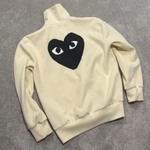 Comme des garçon helzip - Tja! Säljer nu denna riktigt feta beige/krämvita helzip med svarta hjärtat från Comme Des Garçon (CDG). Size L passar även M, modellen på bilderna är 182cm lång ish. Skriv vid funderingar!