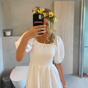 Vit somrig klänning med puffärm - Superfin vit klänning med puffärmar och smockad överdel. Den är perfekt till midsommar eller student. Priset går att diskutera. 