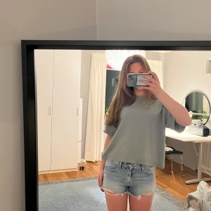 Ljusblå jeansshorts med fransar - Säljer ett par ljusblå jeansshorts med råa franskantade benslut och klassisk femficksdesign. Shortsen har normal passform och är perfekta för sommaren. De är midwaist och har en avslappnad look.