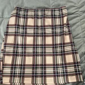 Beige rutig kjol - Säljer en beige kortkjol med rutigt mönster i svart, vitt och rött. Kjolen har en rak passform och är perfekt för dig som gillar klassisk stil med en twist. Superenkel att matcha med både stickade tröjor och t-shirts.