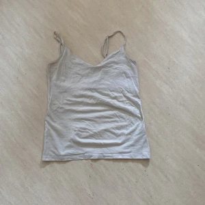 Vit linnetopp från 157 - Säljer ett linne från 157 i storlek S. Toppen har smala axelband och en rak passform, perfekt att matcha med jeans eller kjol. Tillverkad i mjuk bomull för en bekväm känsla. Tyvärr så är linnet ganska uttöjt och missfärgat. 