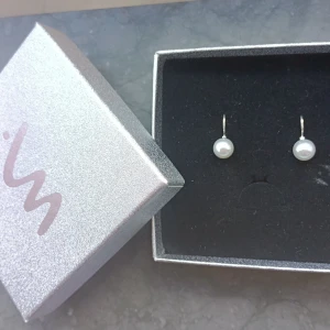 Silverörhängen med pärlor - Säljer ett par stilrena örhängen i silver med vita pärlor. Perfekta för dig som gillar en klassisk och elegant look. Kommer i en snygg ask.