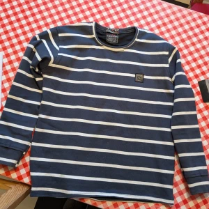 Calvin Klein tröja  - Långärmad tröja med ränder i marinblått och vitt. Tröjan har en rund halsringning och en liten logotyp på bröstet.