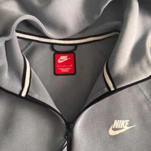 Ljusblå zip-hoodie från Nike - Säljer en stilren ljusblå hoodie från Nike med dragkedja och huva. Jackan har svarta detaljer vid fickorna och en vit Nike-logga på bröstet. Perfekt för en sportig look och enkel att matcha med det mesta. Äkta köpt för 1400kr för 2månader den använd därför säljer jag den för endast 550kr vid snabb affär 500kr