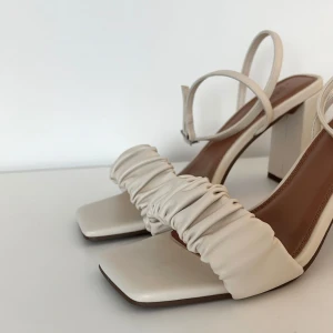 Klacksandaler med rynkning - Säljer ett par halvhöga klacksandaler med rynkning och fyrkantig tå. Justerbar ankelrem. Aldrig använda, enbart provade ett par gånger.