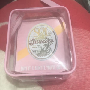 Sol de Janeiro Beija Flor Jet Set kit i rosa necessär - Säljer ett Sol de Janeiro Beija Flor Jet Set kit i en genomskinlig rosa necessär. Kitet innehåller hudvårdsprodukter i ministorlek, perfekt för resan. Necessären har dragkedja och rosa detaljer. Märkets logga syns tydligt på framsidan.