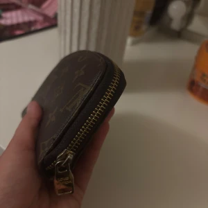 Brun plånbok  - Säljer en brun plånbok guldfärgad dragkedja. Perfekt storlek för kort och mynt, med flera fack inuti. En snygg accessoar för dig som gillar lyxiga detaljer.