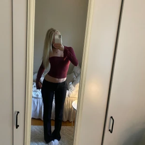 Vinröd croppad topp från Gina Tricot - Säljer en vinröd croppad topp från Gina Tricot med lång ärm och figurnära passform. Toppen har en snygg fyrkantig urringning och är perfekt att styla med höga byxor.