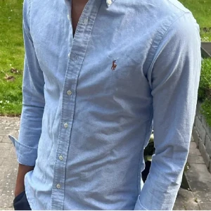 Ljusblå skjorta från Ralph Lauren - Tjaa! Säljer nu min ljusblå skjorta från Ralph Lauren. Storlek S. Den har en broderad logga på bröstet. Skjortan har lång ärm, knappar hela vägen och är i bomull. Jag garanterar att du blir skönast på gähdan med den på. Kan gå ner i pris vid snabb och smidig affär!✌🏼✌🏼mvh👌🏻✌🏼