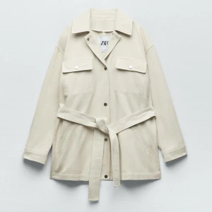 Beige overshirt med bälte från Zara - Stilren beige overshirt från Zara med bälte i midjan och stora bröstfickor med lock. Jackan har knappar framtill och klassisk krage. Perfekt för lager-på-lager och enkel att styla till olika outfits. Har knappt använt den .