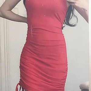 Röd ribbad klänning från SHEIN - Säljer en tight röd ribbad klänning från SHEIN med rynkade sidor och knytband nertill. Klänningen är ärmlös och har en rund halsringning. Perfekt för dig som vill ha en enkel men snygg look. Sitter jättefint på kroppen. Ej använd bara provats en gång. 