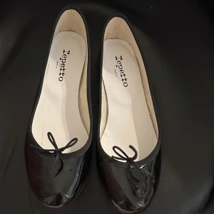 Svarta ballerinaskor från Repetto - Säljer ett par klassiska svarta ballerinaskor från Repetto i lackat skinn. Skorna har rund tå, liten rosett framtill och platt sula. Perfekta för bal, fest eller vardag. Storlek 40 men skulle säga att de passar 38/39 då de är små i storleken! Nypris ca 3000 och näst intill oanvända.