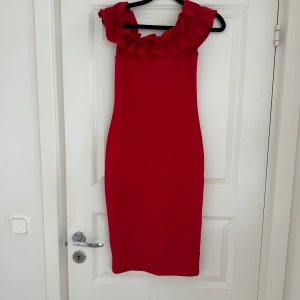 Röd volangklänning från Zara Trafaluc - Säljer en snygg röd klänning från Zara Trafaluc med volangdetalj upptill. Klänningen är ärmlös och har en figurnära passform som passar perfekt till sommarens tillfällen. Kan används off shoulder också 