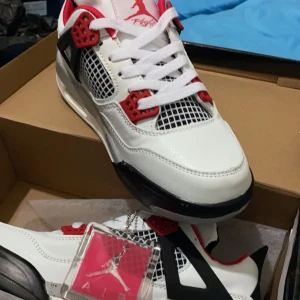 Nike Air Jordan 4 - Säljer ett par Nike Air Jordans 4 sneakers i vitt med svarta och röda detaljer. Skorna är 2 år gamla men ganska oanvända.