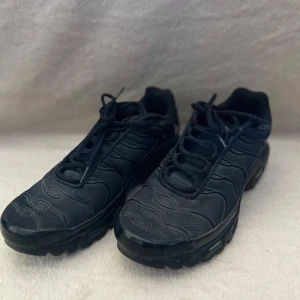Nike Air Max Plus Tn helsvarta sneakers - Säljer ett par helsvarta Nike Air Max Plus Tn sneakers med klassisk vågig design och synlig luftdämpning i sulan. Skorna har snörning och diskret Tn Air-logga bak. Skorna har använts inte alls många gånger och därmed finns det inga som helst defekter! Efter en snabb tvätt är dom helt i nyskick. Perfekta för dig som gillar en sportig och stilren look. *Äkta*