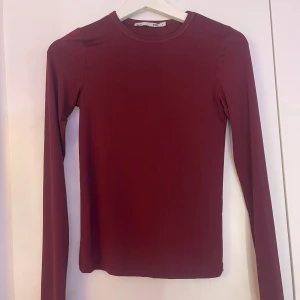 Mörkröd långärmad topp - Säljer en enkel och stilren mörkröd långärmad topp med rund halsringning. Perfekt att matcha med jeans eller kjol. Tunn och stretchig i materialet, sitter tight mot kroppen. Endast använd 1 gång.
