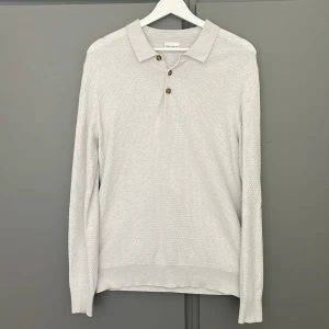 Ljusgrå stickad pikétröja från John Henric - Säljer en ljusgrå stickad pikétröja från John Henric. Tröjan har lång ärm, klassisk krage och tre bruna knappar framtill. Materialet är en blandning mellan 85% bommul och 15% kashmir. Skick 10/10. Nypris: 1000kr
