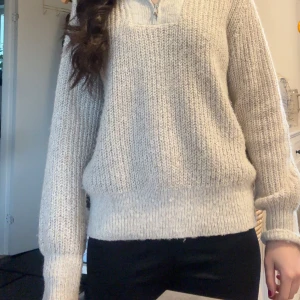 Beige stickad polotröja med dragkedja(ser mörk ut på dem två sista bilderna eftersom att lampan inte funkar, den är inte så mörk) - Mysig beige stickad polotröja med halv dragkedja framtill. Tröjan har lång ärm och bred ribbad mudd vid ärmslut och nederkant. Perfekt för lager-på-lager och en avslappnad stil.