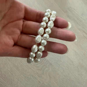 Pärlarmband i vitt - Två elastiska armband med vita pärlor i olika former. Perfekta att bära tillsammans eller var för sig för en stilren och klassisk look.