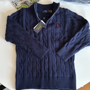 Ralph lauren half zip - Säljer en mörkblå kabelstickad tröja från Ralph Lauren med halv dragkedja och klassisk röd logga broderad på bröstet. Liten i storlek M men sitter som S. 10/10 kvalité och endast testad på. Hör av er vid minsta intresse🌟🤩
