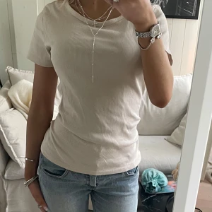 Beige ribbad t-shirt - Säljer en stilren beige ribbad t-shirt med korta ärmar. Perfekt för en avslappnad look. Passar bra till jeans eller kjol.