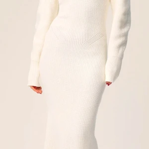 Vit stickad långklänning - Säljer en vit stickad långklänning med lång ärm och rund hals. Klänningen har en figurnära passform och är tillverkad i ett mjukt, ribbat material som ger en stilren och elegant look. Använd 1 gång. Nypris 1695kr säljer för 600kr. Strl 32 men passar mig som har 34/36 