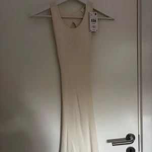 Ljusbeige ribbad långklänning från mango. aldrig använd  - Säljer en ljusbeige ribbad långklänning från mango med ärmlös design och rund halsringning. Klänningen har en snygg cut-out detalj framtill och öppen rygg. Perfekt för sommarens alla tillfällen!