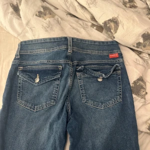 Blå jeansbyxor från hm - Säljer ett par klassiska blå jeans från hm med raka ben och normal passform. Byxorna har fem fickor, knapp- och dragkedjestängning samt snygga detaljer på bakfickorna.