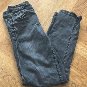 Grå jeansbyxor från Mango - Säljer ett par snygga grå jeans från Mango med klassisk femficksdesign och silverfärgad knapp. Byxorna är slim fit och är perfekta för en avslappnad stil. Materialet är mjukt och bekvämt och storleken passar mellan 160-173cm beroende på hur tajta man vill att de ska va!