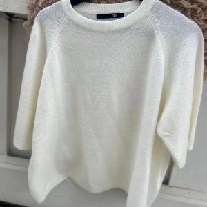 Vit stickad tröja från 157 - Mysig vit stickad tröja från 157 med rund halsringning och korta ärmar. Perfekt för att enkelt matcha med olika outfits. Mjuk och skön känsla tack vare det stickade materialet. Oanvänd. SKRIV INNAN DU KÖPER.