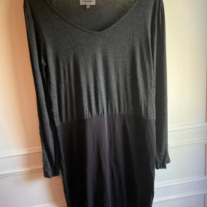 Mörkgrå klänning från Zalando Essentials - Säljer en stilren mörkgrå klänning från Zalando Essentials. Klänningen har en v-ringad hals och långa ärmar, perfekt för en avslappnad look. Den är tillverkad i ett mjukt material som ger en bekväm passform. Oanvänd!