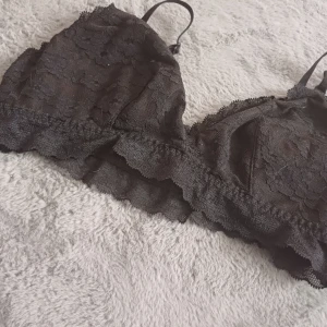 Svart spets bralette - Säljer en elegant svart bralette i spets med justerbara axelband. Perfekt för en stilren och bekväm look. Den har en mjuk och följsam passform.