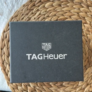 TAG Heuer silverfärgad klocka i originalask - Säljer en stilren TAG Heuer klocka i silverfärg med metallarmband. Klockan levereras i originalask med tillhörande instruktioner och garantikort. Klassisk design med rund urtavla och tydliga markeringar. Den har aldrig provats eller plockats ur förpackningen. Den är köpt för 1 månad sedan och har aldrig använts. Den är värd 20650. Det är en damklocka men kan bäras av en man. Möts upp vid köp