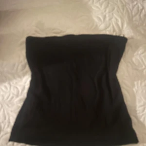 Svart tubtopp - Säljer en stilren svart tubtopp från cubus med silikon högst upp som gör att toppen hålls på plats. Perfekt för att matcha med olika outfits. Toppen är enkel och elegant, vilket gör den till ett mångsidigt plagg i garderoben.
