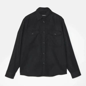 J.Lindeberg - Overshirt - Snygg svart overshirt från J.Lindeberg med långa ärmar och knappar framtill. Perfekt för lager-på-lager-stil. Två bröstfickor med knappar ger en cool touch. Passar både till vardags och mer uppklädda tillfällen. Skick - 8,5/10