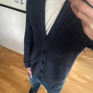 Mörkblå Cardigan  - Säljer en mörkblå stickad cardigan från Hollister med knappar framtill och två fickor. Mycket skön cardigan i utmärkt skick. Perfekt att slänga på sig över en t-shirt eller skjorta. Storlek S men sitter även bra som M.