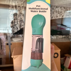 Pet Multifunctional Water Bottle multifunktionell vatten flaska för hundar - Säljer en grön multifunktionell vattenflaska för husdjur. Flaskan har en inbyggd skål för vatten och ett fack för torrfoder eller snacks. Perfekt att ta med på promenader eller resor med hund eller katt.