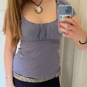 Lila/grå kortärmad topp - Säljer en söt lila topp med korta ärmar och knappar framtill. Säljer då den inte används skriv gärna vid frågor!🤗✌️