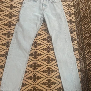 Ljusblå jeans från Weekday - Säljer ett par ljusblå jeans från Weekday i modellen Pine Regular Tapered. De har en klassisk femficksdesign och är tillverkade i denim. Perfekta för en avslappnad stil.