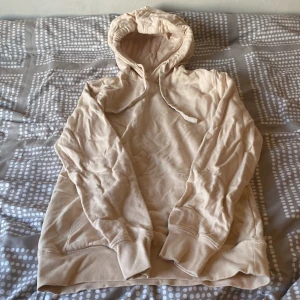 Beige hoodie från C - Säljer en beige hoodie med huva och dragsko från märket C. Tröjan har långa ärmar, ribbade muddar och är gjord i mjukt, fleeceliknande material på insidan. Perfekt för en avslappnad stil.
