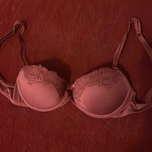 Röd bh från Hunkemöller - Säljer en jätyefin röd bh från Hunkemöller med vackra spetsdetaljer. Den har justerbara axelband och en klassisk design som ger bra stöd. Storlek 75A.