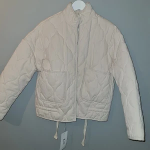 Beige quiltad jacka med dragkedja - Säljer en beige quiltad jacka med dragkedja och två stora fickor framtill. Jackan är köpt på vinted med varken använde av mig eller förra ägaren. 