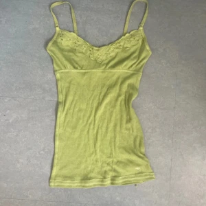 Ljusgrön babydoll linne med spets från Abercrombie & Fitch - Säljer en ljusgrön linnetopp från Abercrombie & Fitch med tunna axelband och spetsdetaljer vid bysten. Mindre gul och mer grön irl. Storlek s men funkar bra för xs också