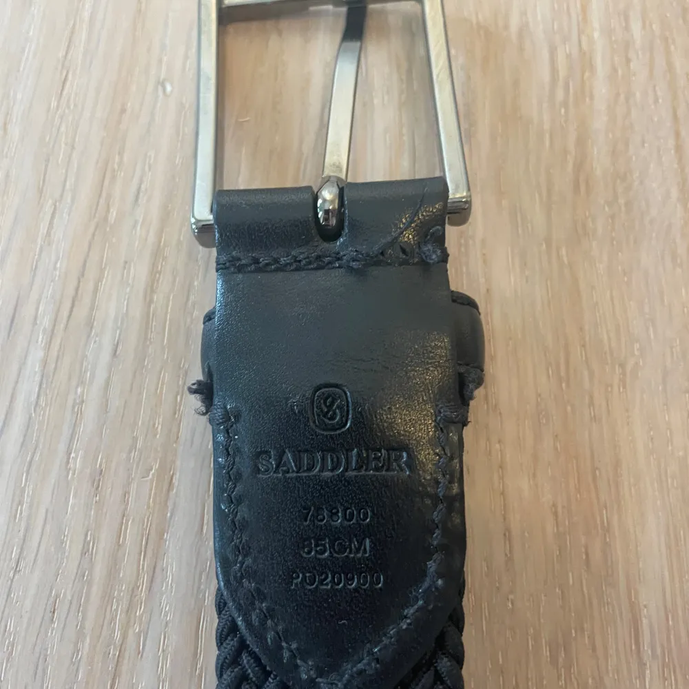Snyggt svart flätat bälte från saddler med ett stilrent silverfärgat spänne. Bältet har detaljer i skinn vid ändarna som ger en elegant touch. Perfekt för att komplettera din outfit. Lite trådar sticker ut vid spännet men annars mycket bra skick! (85cm). Asusteet.