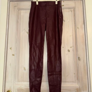 Vinröda skinnbyxor från New Yorker - Snygga vinröda skinnbyxor från New Yorker med en tight passform. Byxorna har en dragkedja på sidan för enkel på- och avtagning.