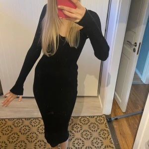 Svart stickad ribbad klänning - Snygg svart stickad ribbad klänning med lång ärm och v-ringad design. Klänningen har en tight passform som framhäver figuren. Jag är 176 cm lång och den slutar liten bit under knäna. Säljer då den tyvärr inte kommer till användning mer💓