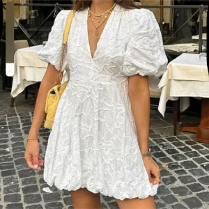 Vit klänning  - Säljer en söt vit klänning med puffiga kortärmar och v-ringning. Perfekt för studenten eller inför sommaren!! Liten fläck längst uppe på baksidan men den syns knappt 